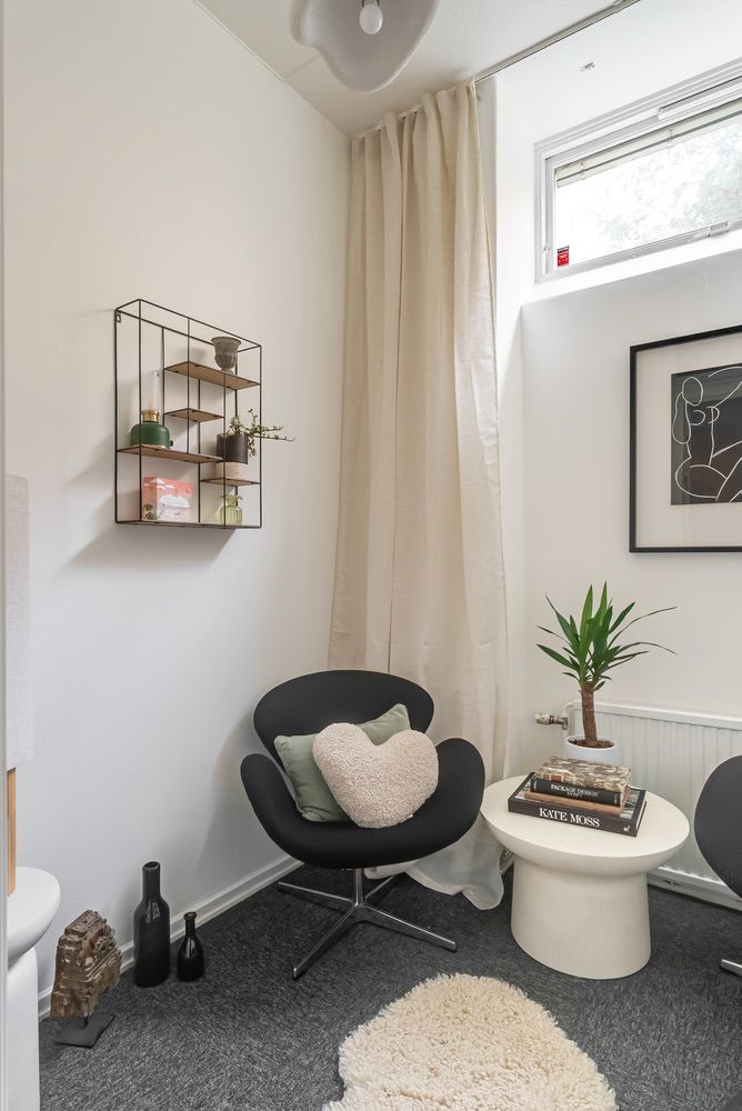 Stilren läshörna med svart fåtölj och väggdekoration